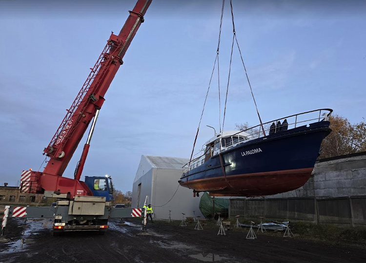 Truck-mounted crane hoisting marine vessel during maintenance operation